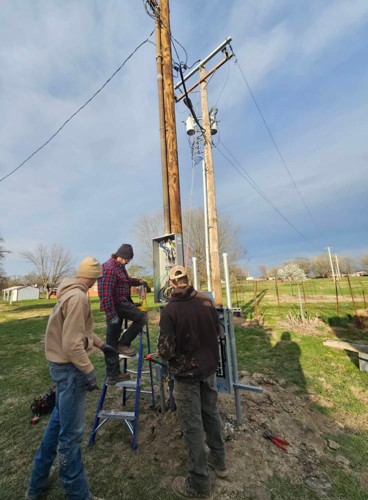 Woman in straw hat smiles, holding wine glass near a lake.