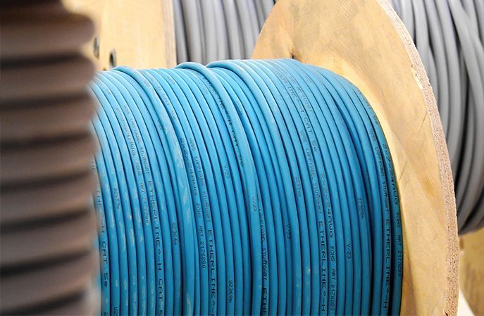 A close up of a spool of blue cable on a wooden spool.