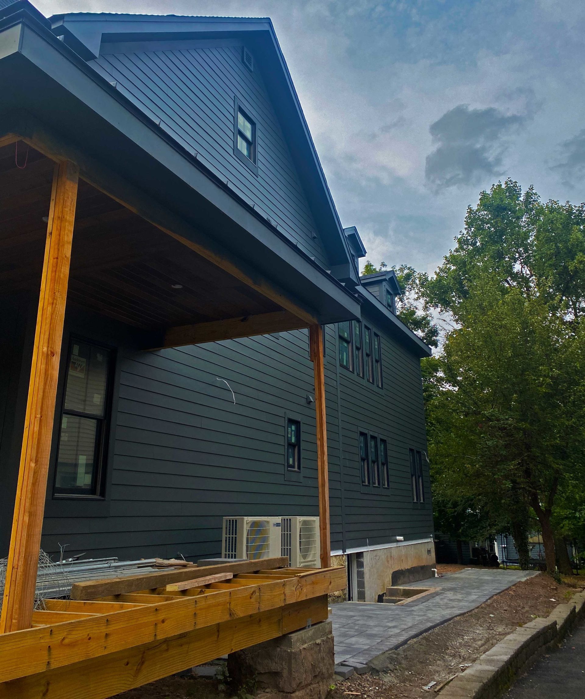 A black house with a wooden porch and trees in the background
