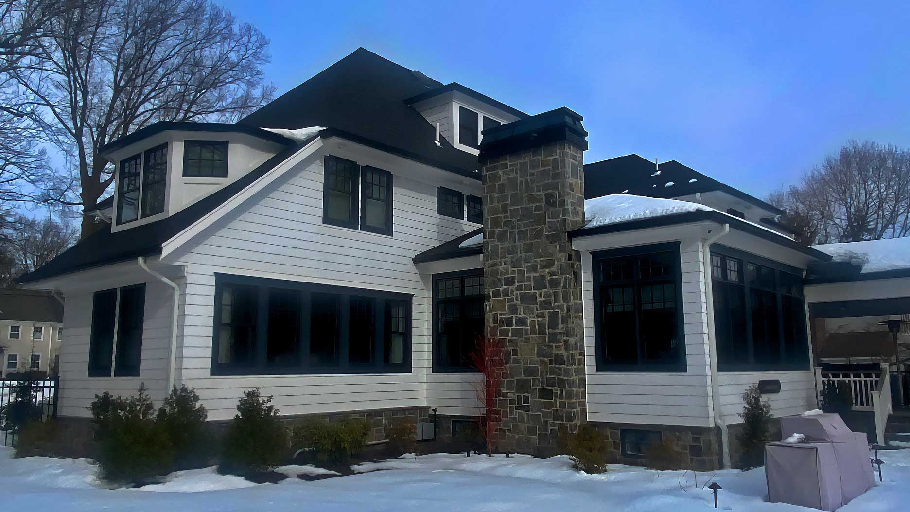 A large white house with a stone chimney in the snow