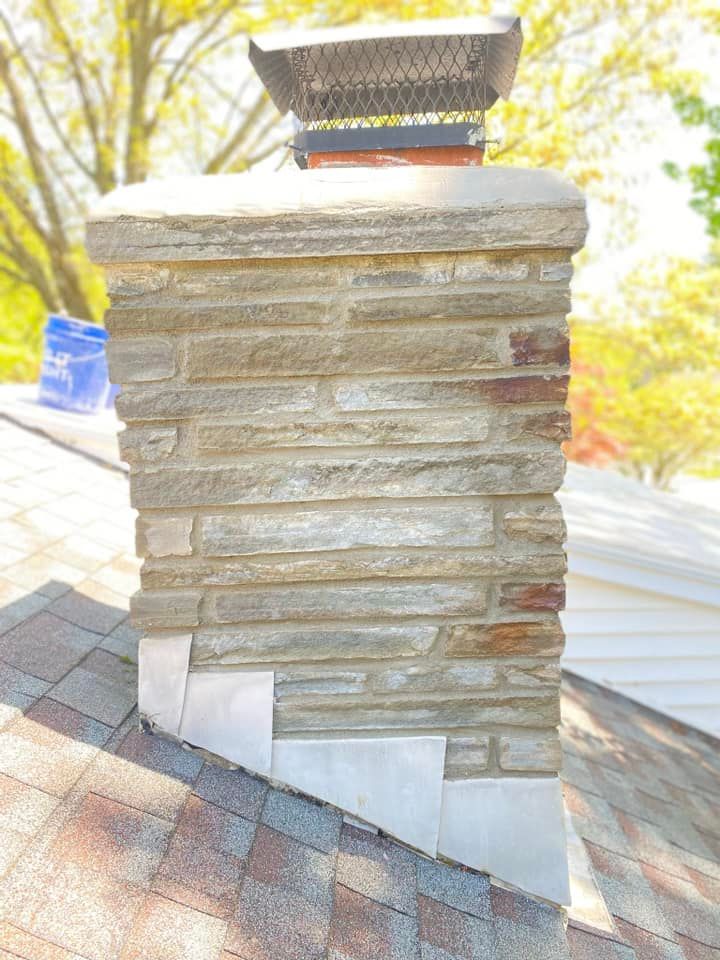 Stone chimney with a metal cap on a roof.