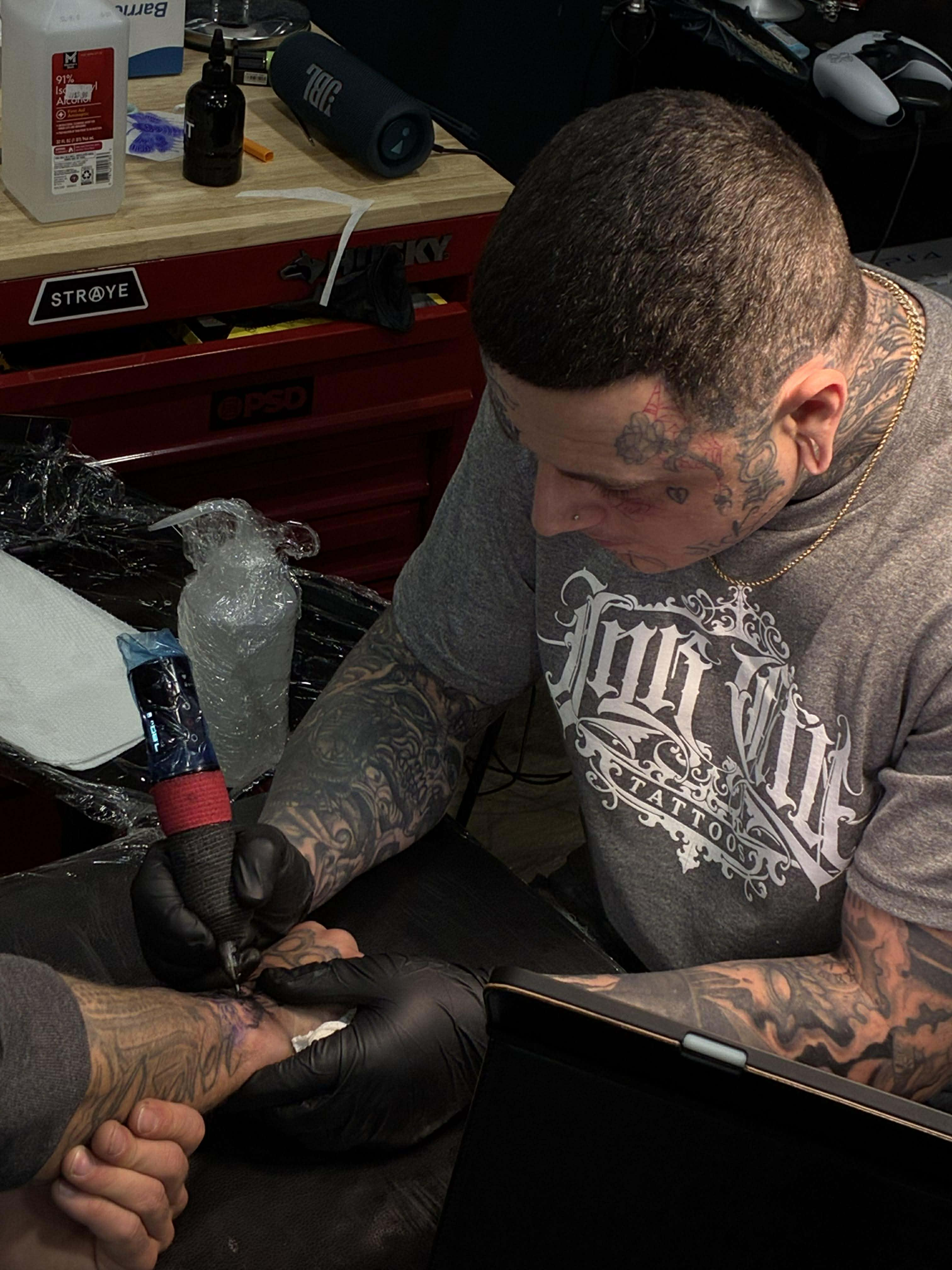 Man with a face tattoo and a head tattoo, white shirt, indoors.