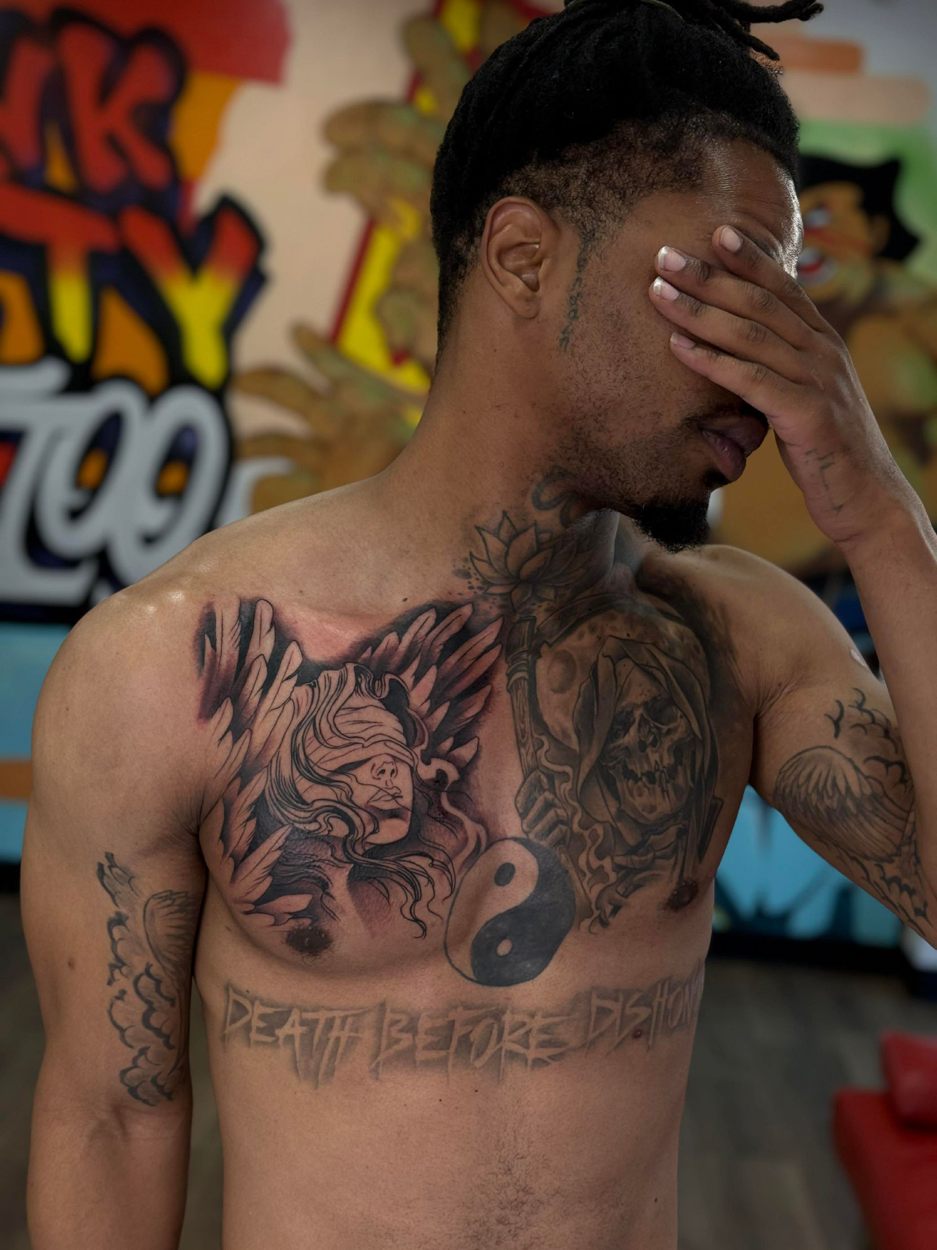 Man with chest tattoos covering face. Studio backdrop: