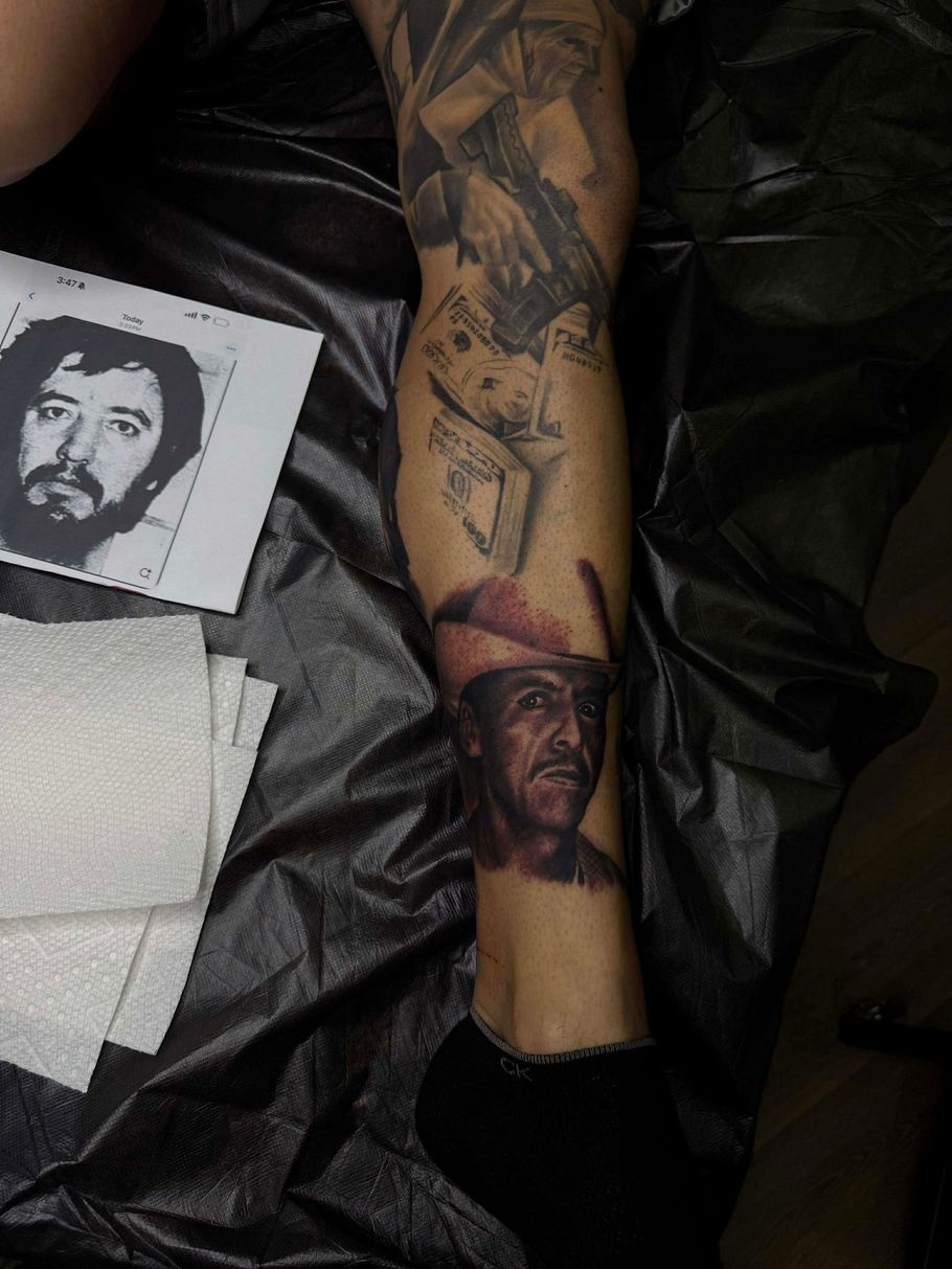Leg tattoo with portraits, money, and other elements, possibly criminal themed.