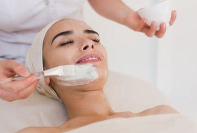 A woman is getting a facial massage with her eyes closed.