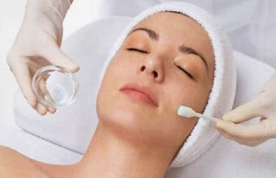 A woman is getting a facial massage with her eyes closed.