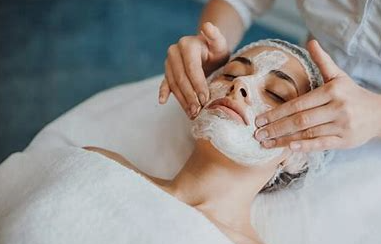 A woman is getting a facial massage with her eyes closed.