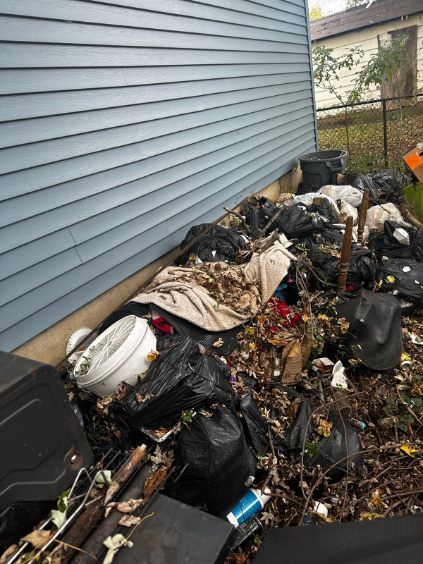 A pile of trash is sitting in front of a house.