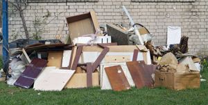 A pile of trash is sitting in the grass in front of a brick wall.