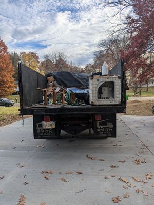 A dump truck filled with junk is parked in a driveway.