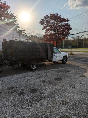 A white truck with a black bed is parked in a gravel lot.