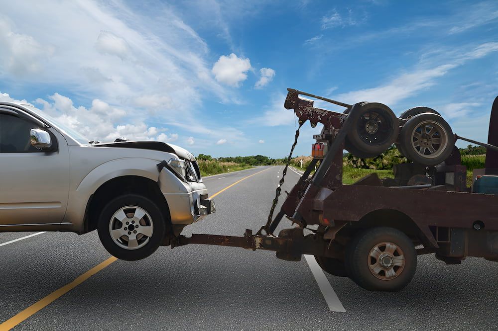 A Tow Truck Is Towing A Car On The Side Of The Road — Ollies Towing & Shipping Container Sales in Kingaroy, QLD