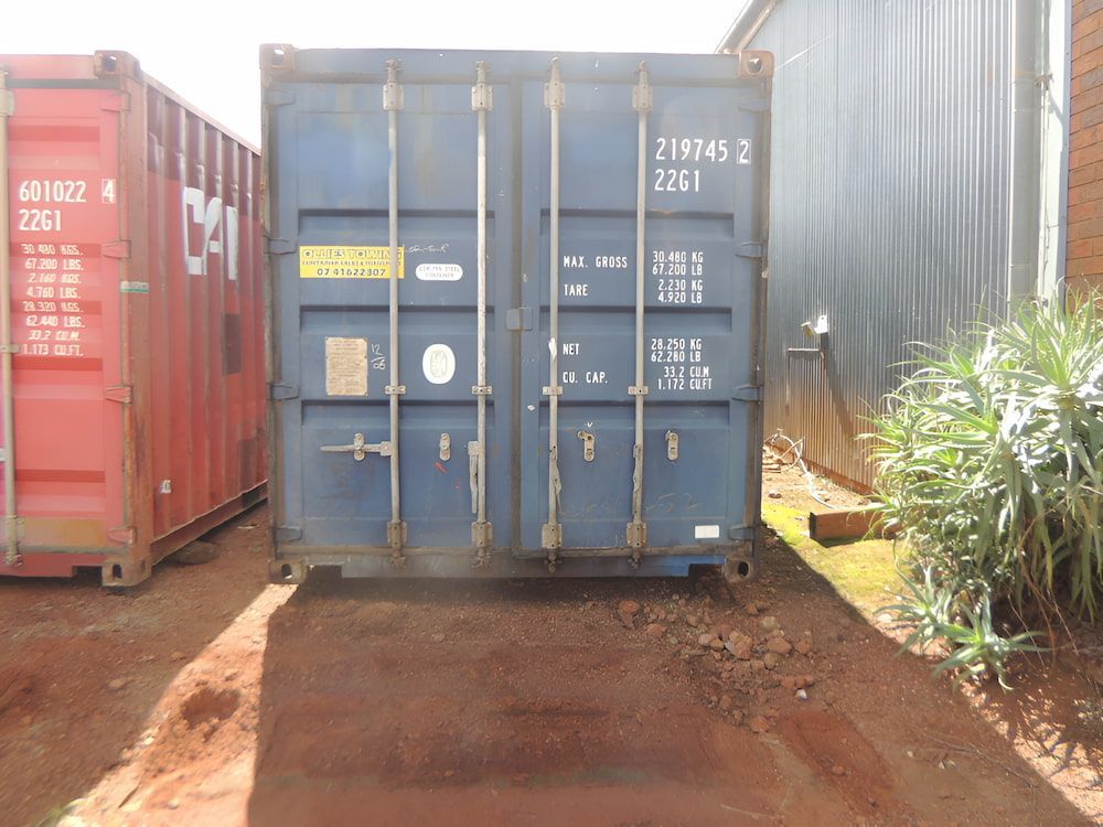 A Blue Shipping Container Is Parked Next To A Red Container — Ollies Towing & Shipping Container Sales in Nanango, QLD