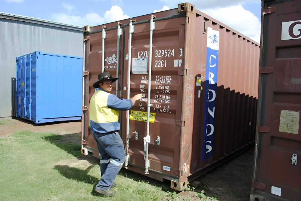 A Man Is Opening The Door Of A Shipping Container — Ollies Towing & Shipping Container Sales in Kingaroy, QLD