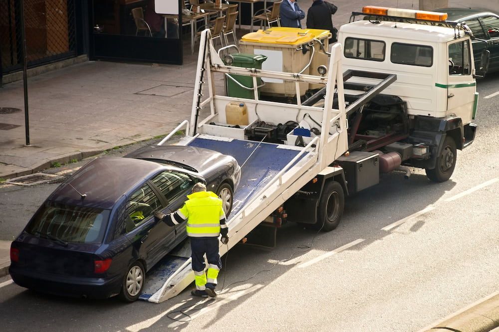 A Tow Truck Is Towing A Car On The Side Of The Road — Ollies Towing & Shipping Container Sales in Kingaroy, QLD