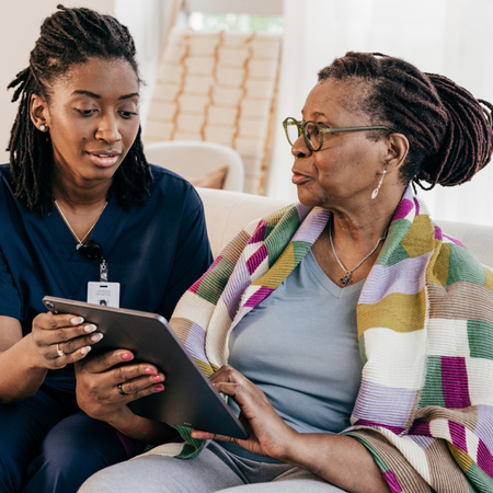 A nurse with a stethoscope around her neck is using a tablet