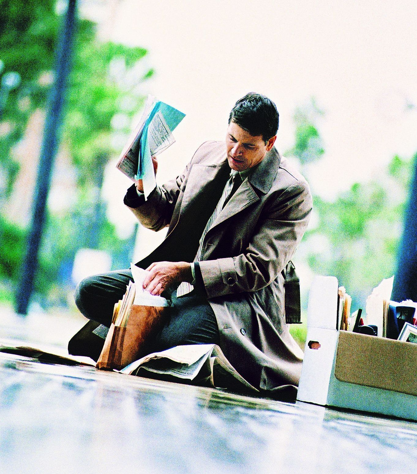 a man in a trench coat is packing his office possessions
