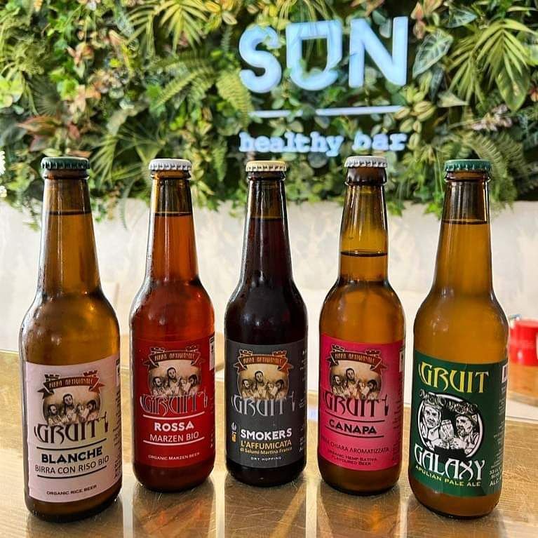 Cinque bottiglie di birra Gruit sono allineate su un tavolo
