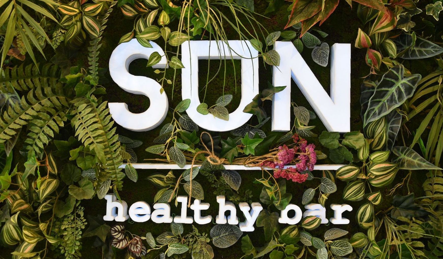 Un cartello per un bar salutare circondato da piante.