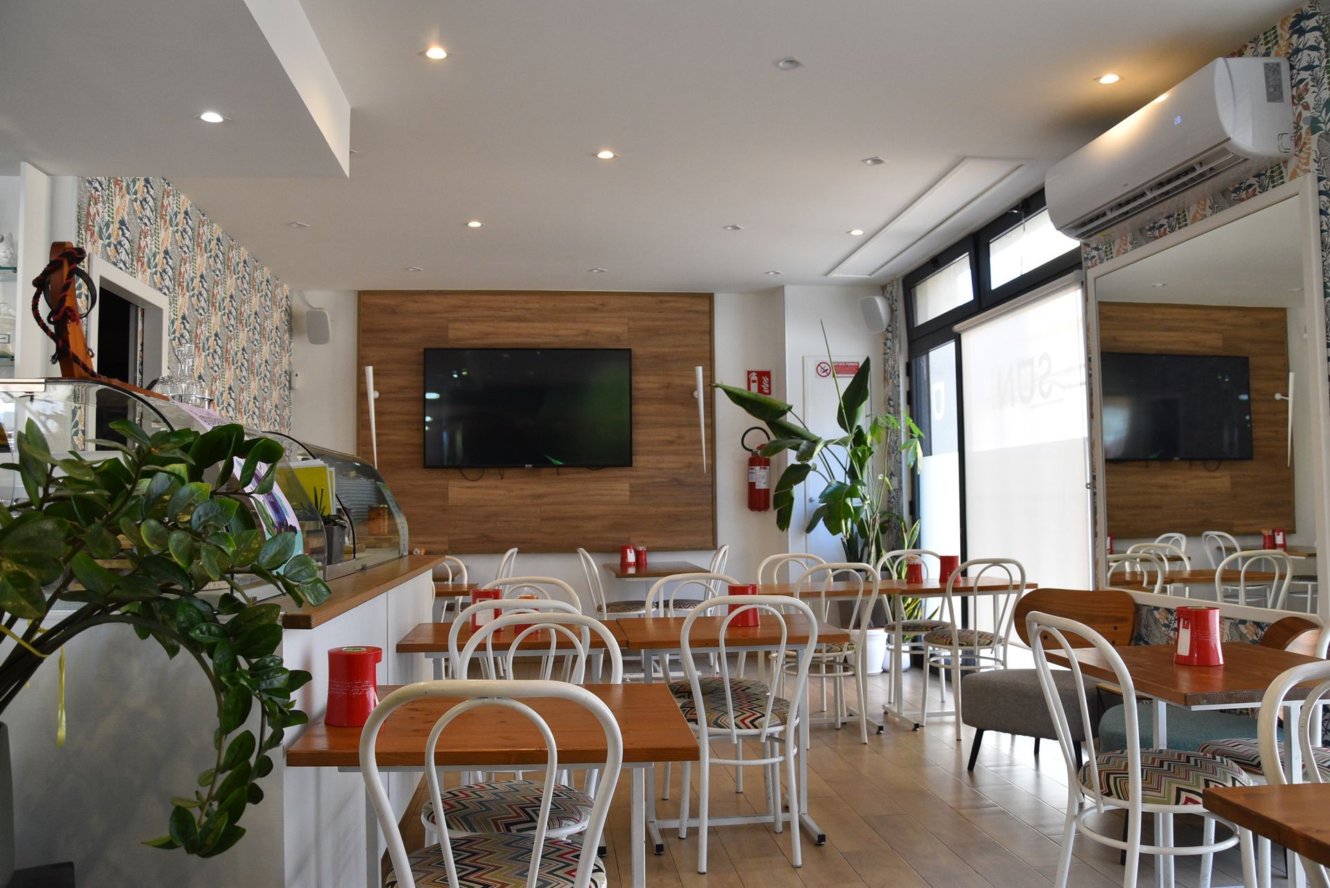 Un ristorante con tavoli e sedie e una TV a schermo piatto sulla parete.