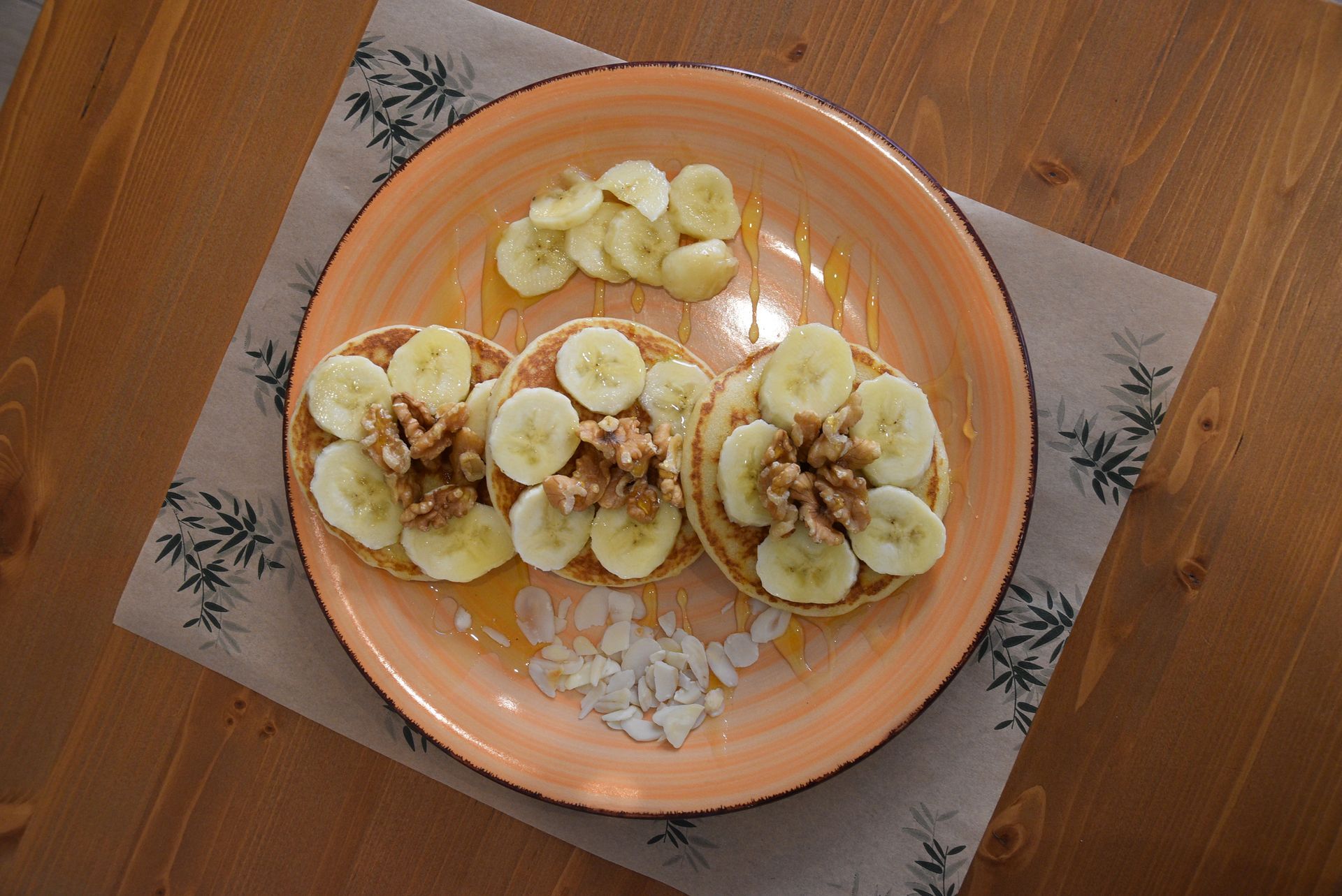 Un piatto di pancake con banane e noci su un tavolo di legno.