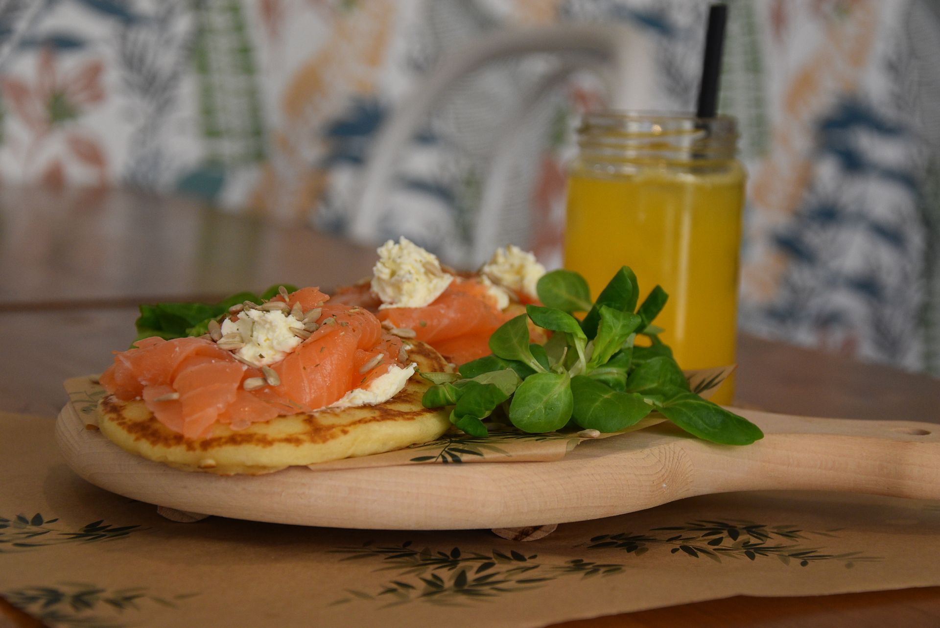 Un cucchiaio di legno con sopra una frittella e un bicchiere di succo d'arancia.