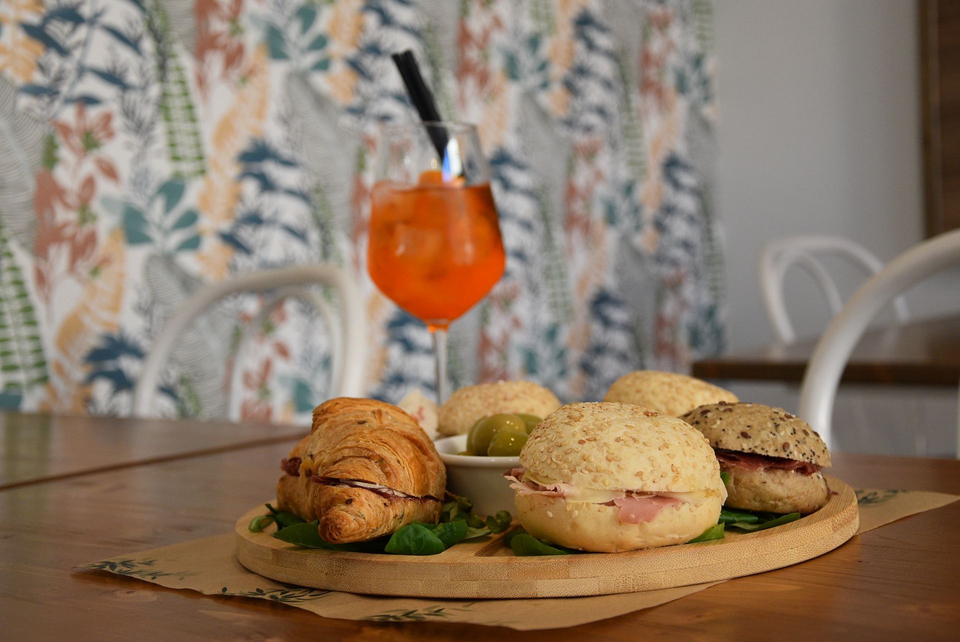 Un tagliere di legno con sopra dei panini e una bevanda su un tavolo.