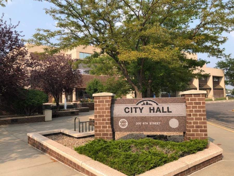 A city hall sign is sitting in front of a building.
