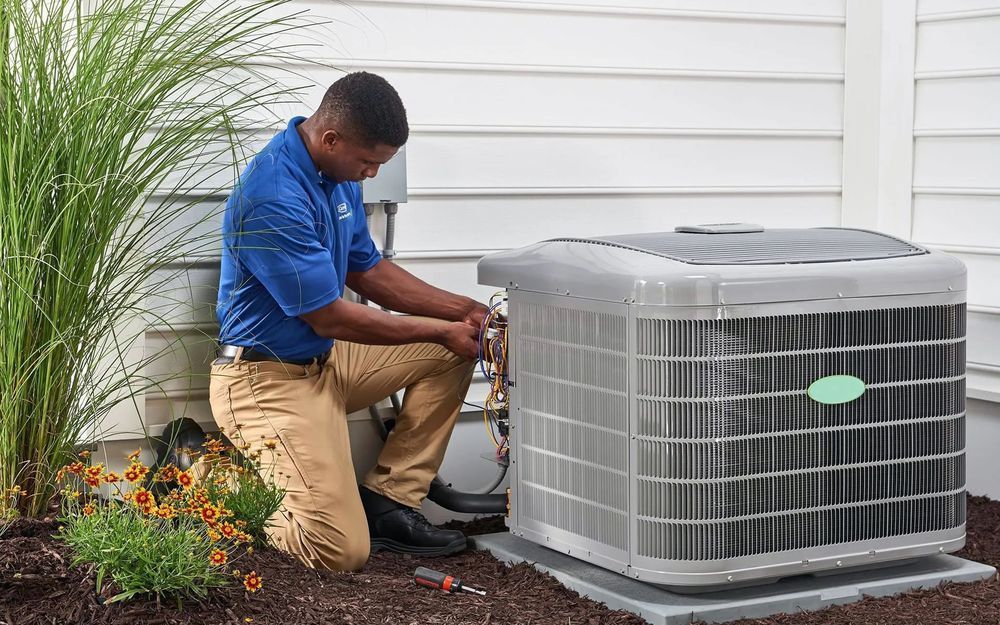 A man is working on an air conditioner outside of a house.