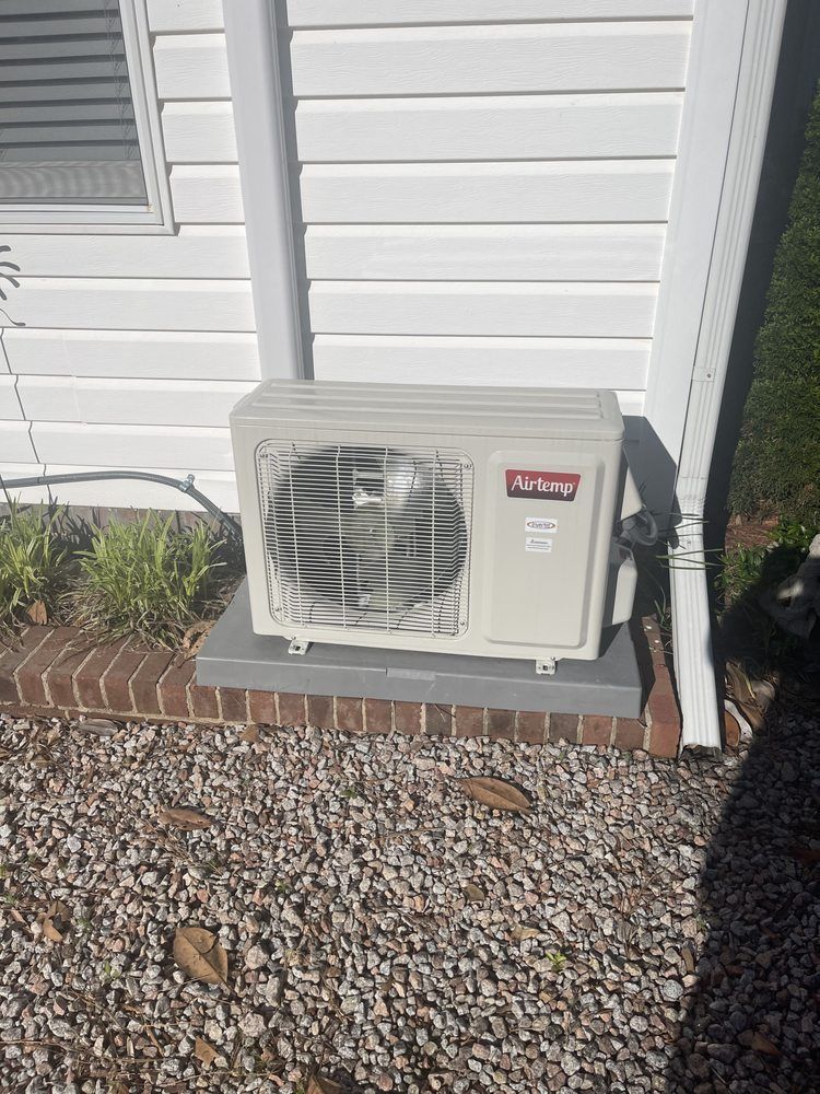 A white air conditioner is sitting on the side of a house.