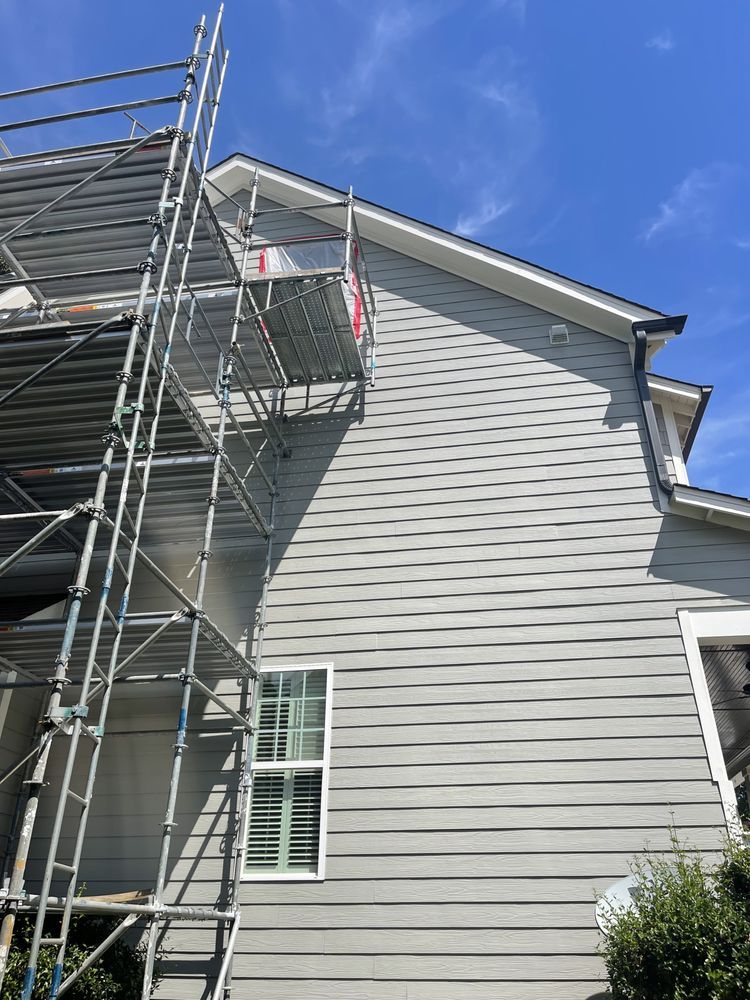 A house with scaffolding on the side of it is being painted.
