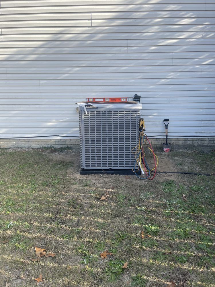 An air conditioner is sitting in the grass in front of a house.