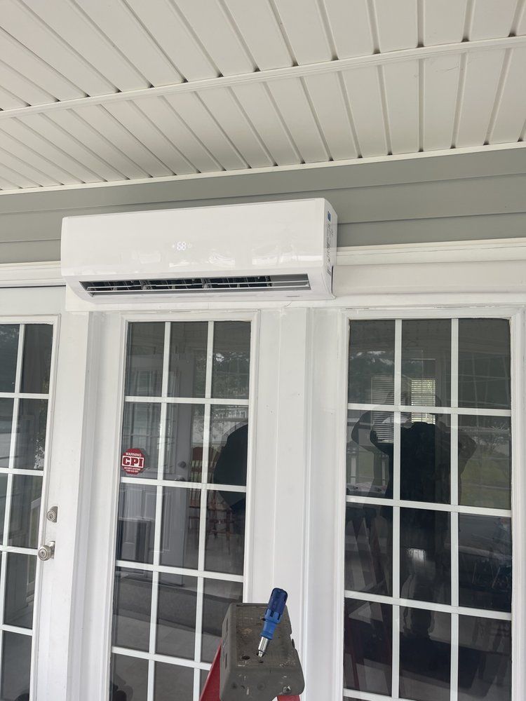 A white air conditioner is mounted on the side of a sliding glass door.