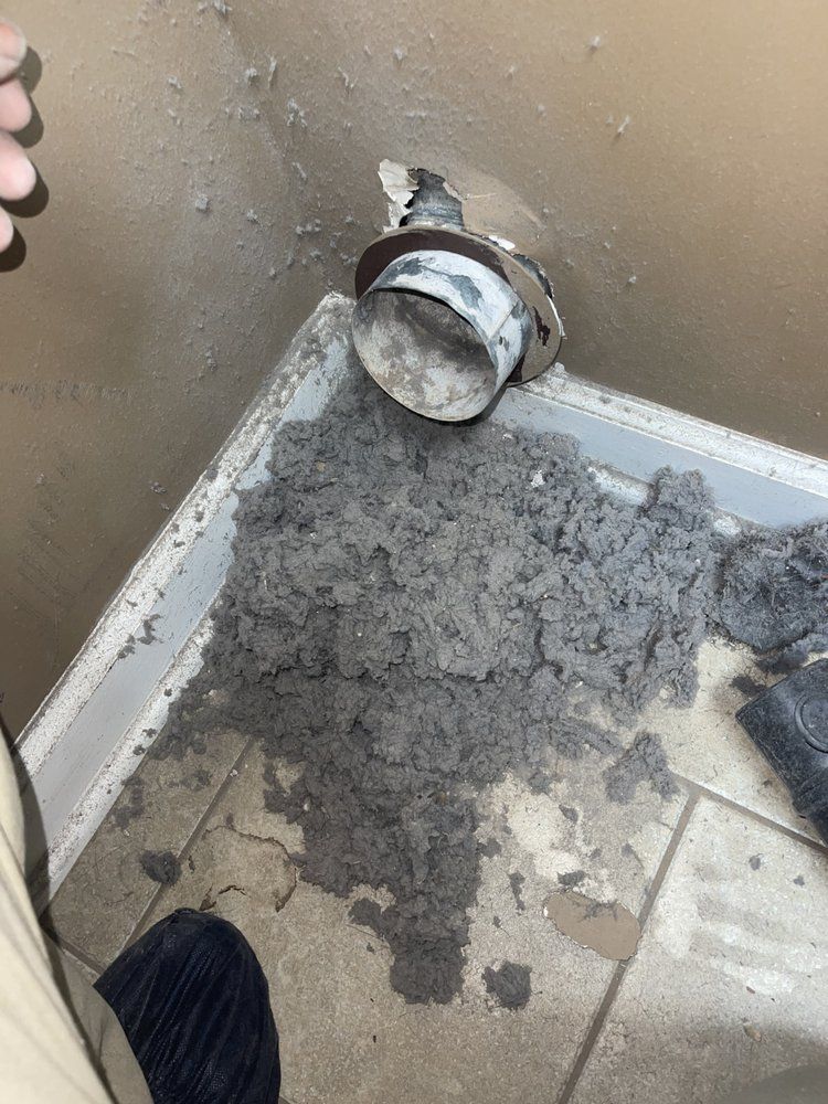 A person is cleaning a dryer vent with a vacuum cleaner.