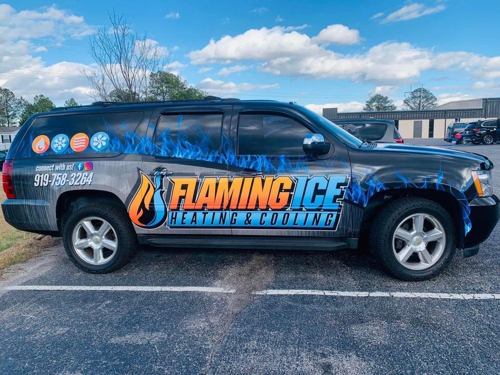 A flaming ice heating and cooling van is parked in a parking lot.