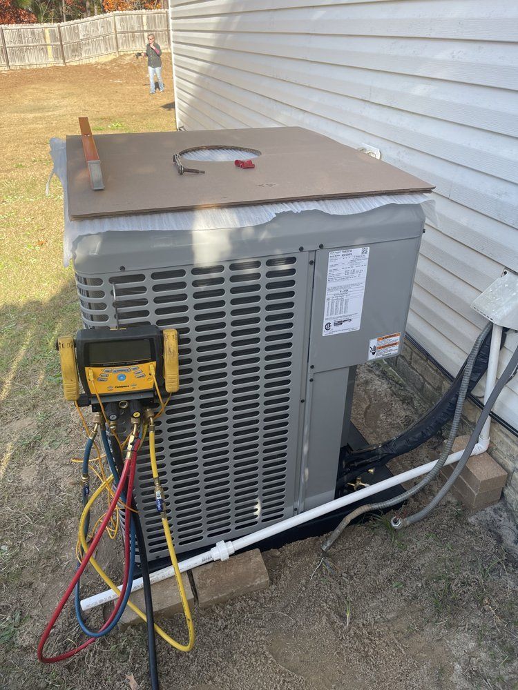 An air conditioner is being installed on the side of a house.