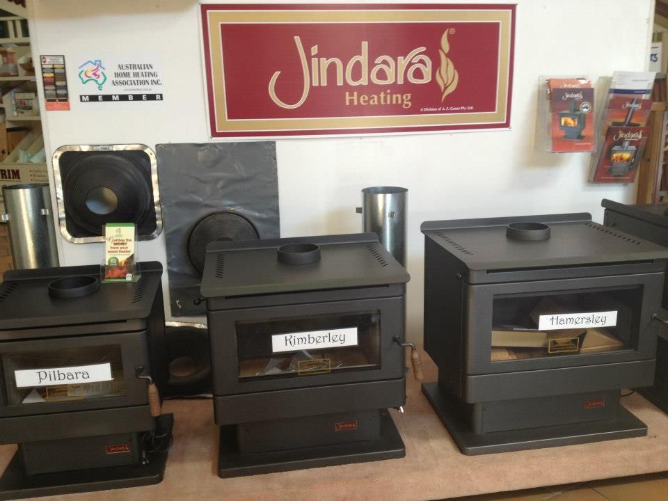 A sign for jindara heating hangs above a display of stoves