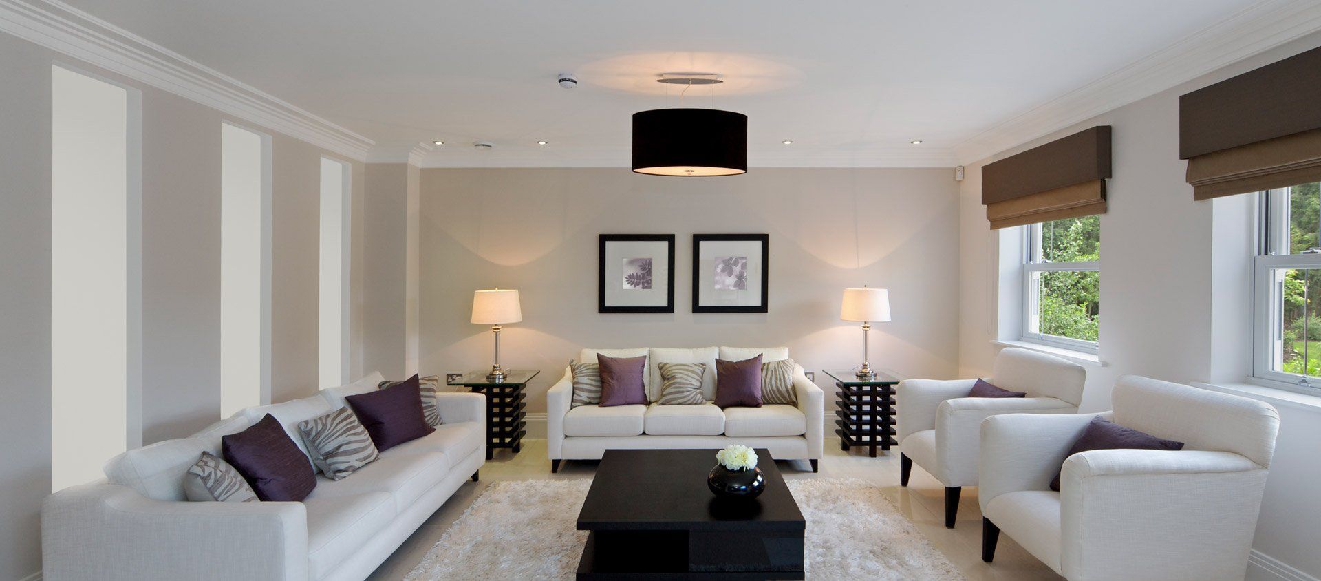 A living room with white furniture and purple pillows