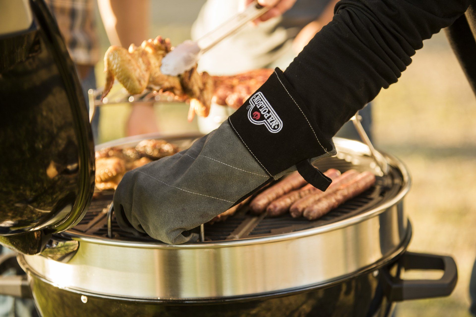 A person wearing an oven mitt is cooking food on a grill.