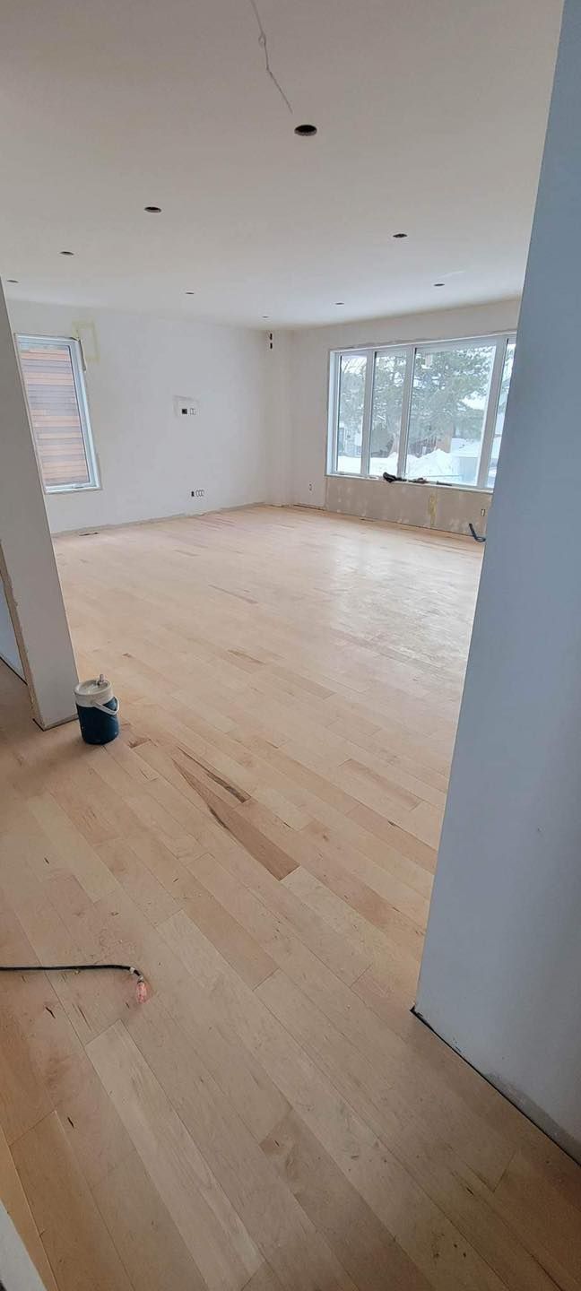 Une grande pièce vide avec du parquet et des murs blancs.