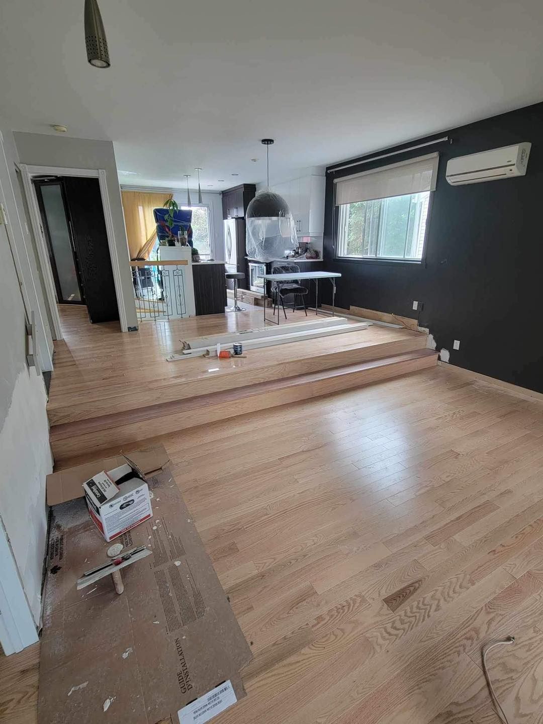 Un salon avec parquet et murs noirs.