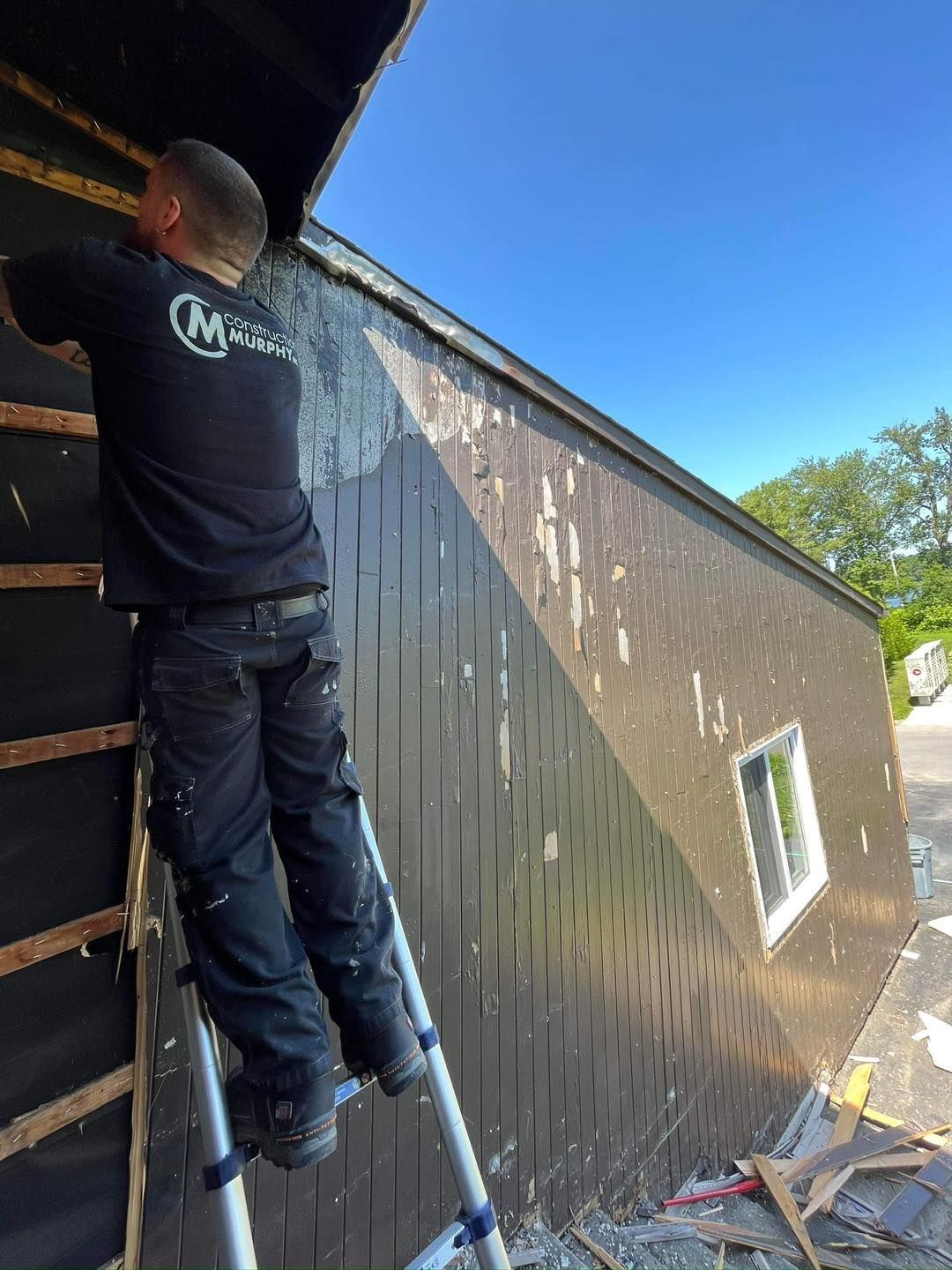 Un homme se tient debout sur une échelle à côté d'un bâtiment.
