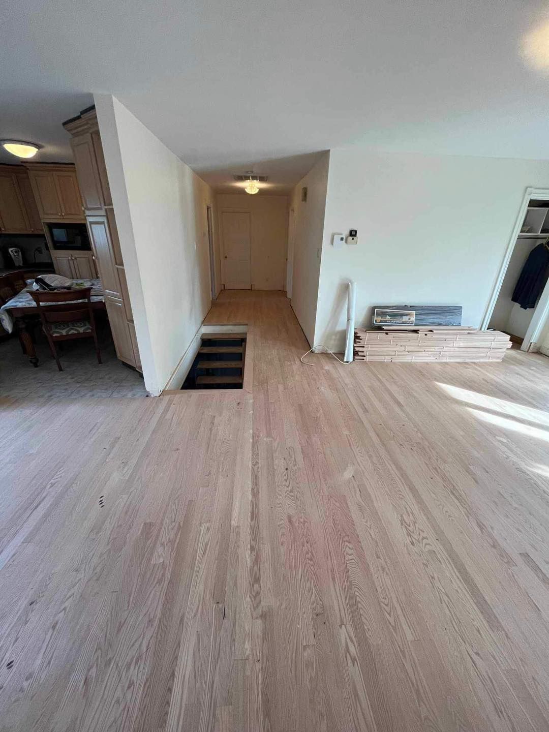 Un salon avec parquet et escalier menant à un couloir.