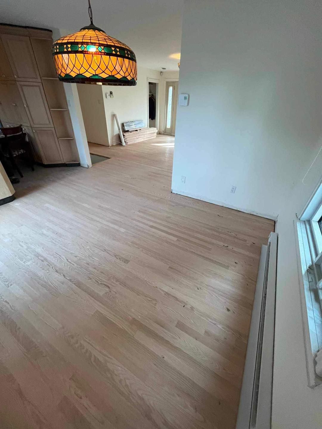 Un salon avec parquet et une lampe en vitrail suspendue au plafond.