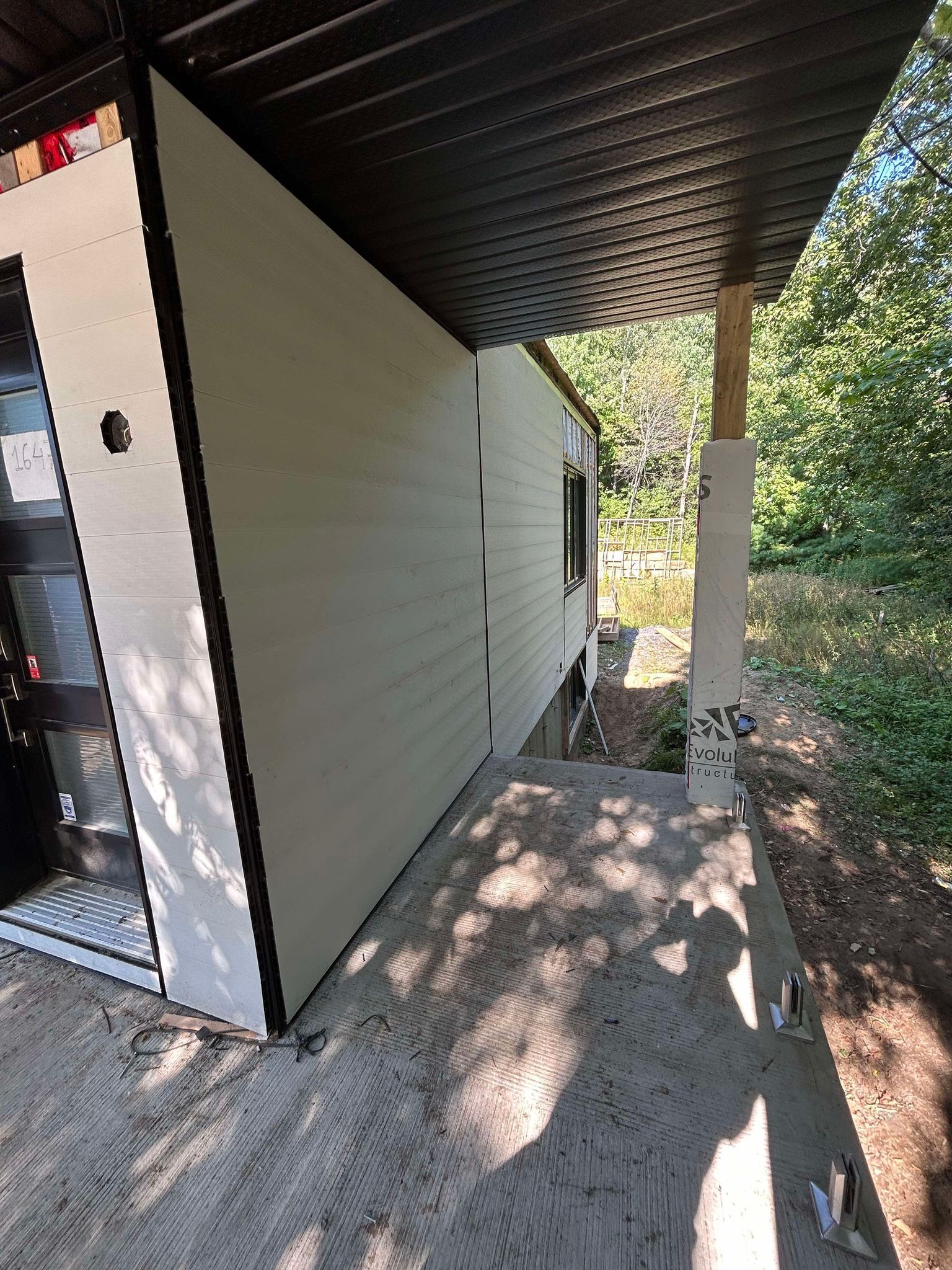 Une maison blanche avec un toit noir et un porche.