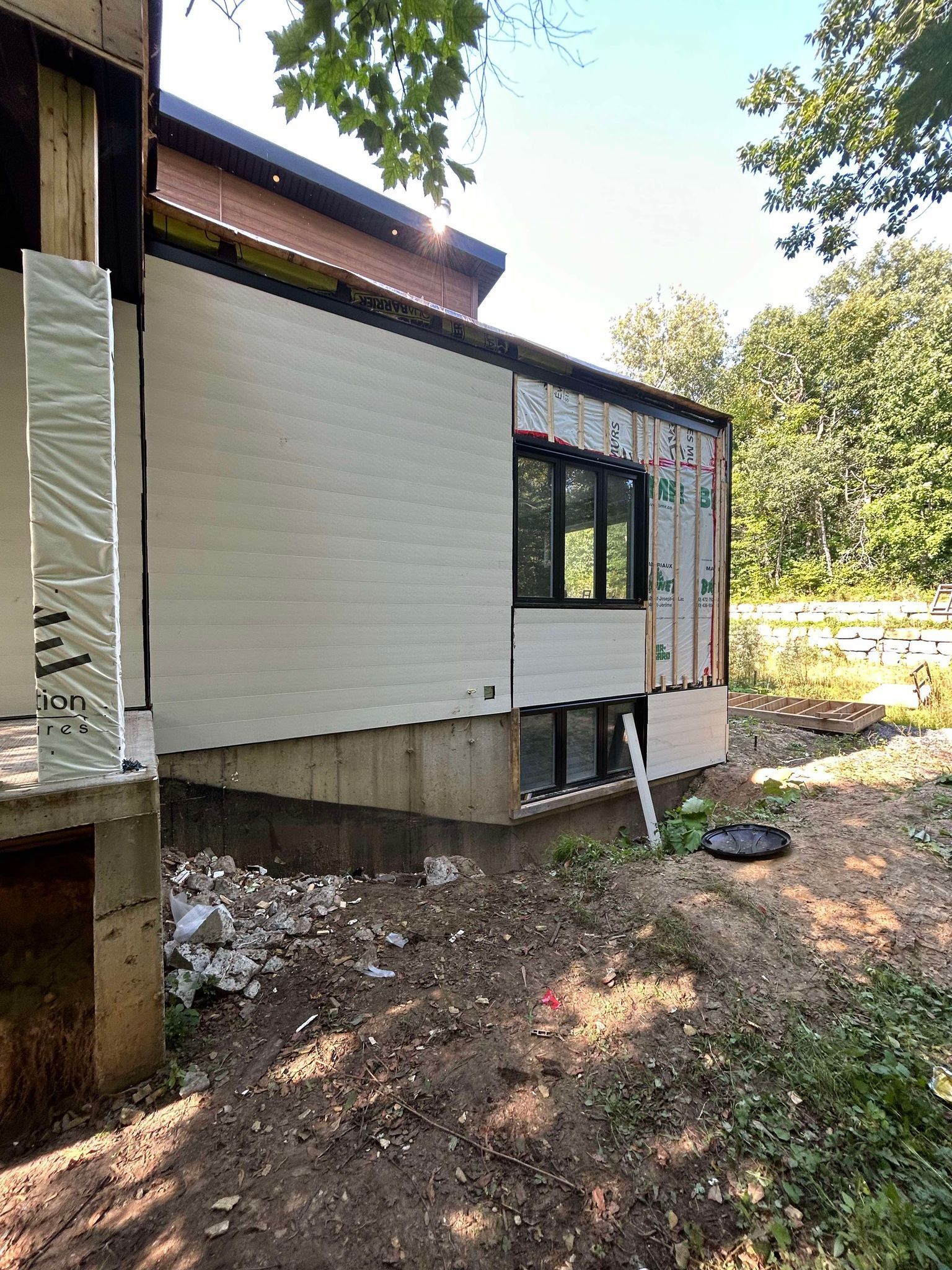 Une maison avec beaucoup de fenêtres est en construction dans les bois.