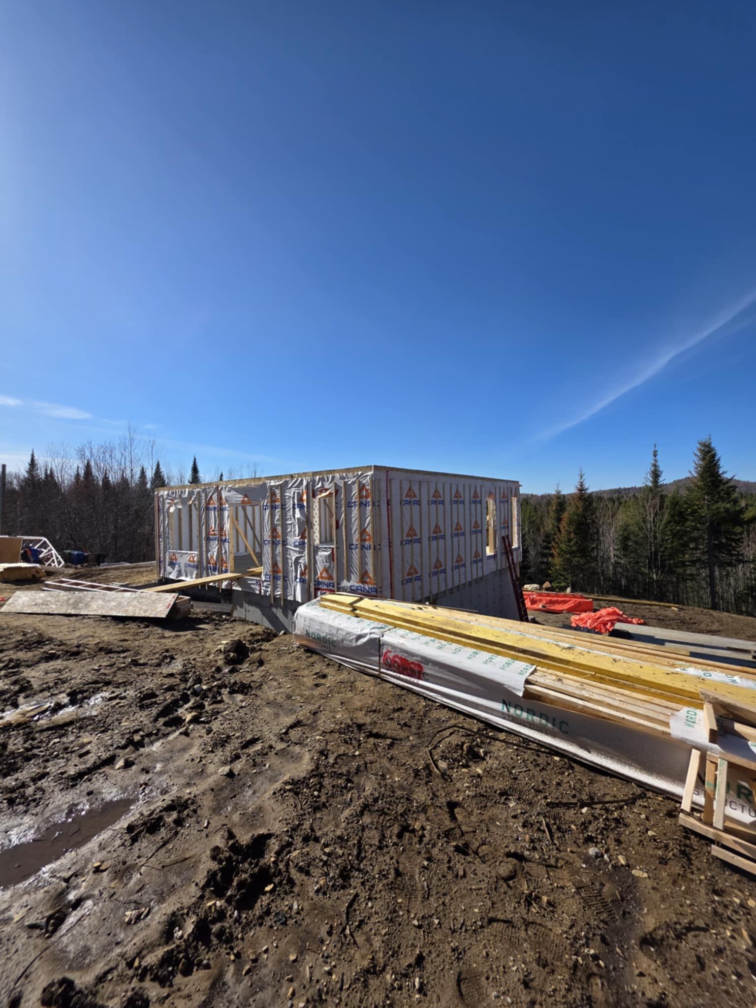 Une maison est en construction au milieu d'un champ boueux.