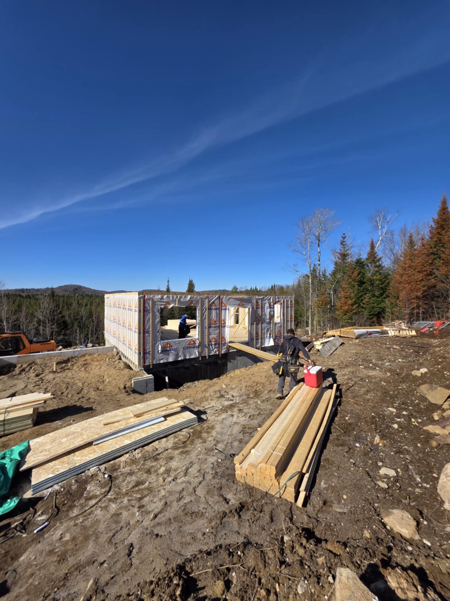 Un homme se tient debout dans la terre devant une maison en construction.