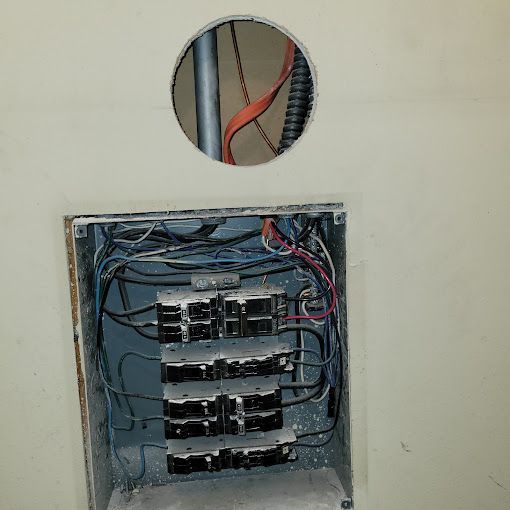 A electrical box with a hole in the wall and wires coming out of it.