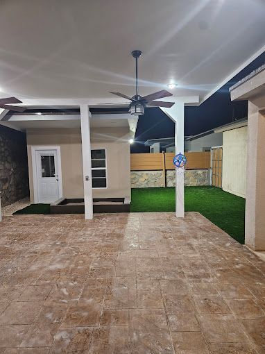 There is a ceiling fan in the backyard of a house.